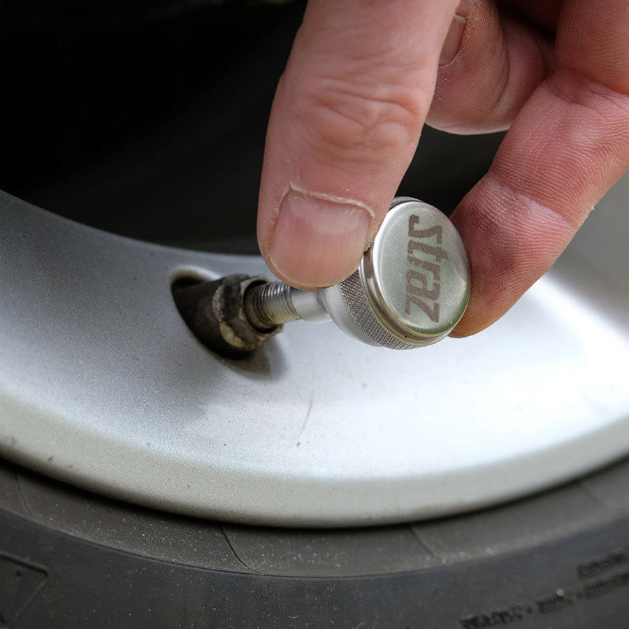 Person using a Straz Components Schrader Valve Core Remover on a car auto truck wheel.