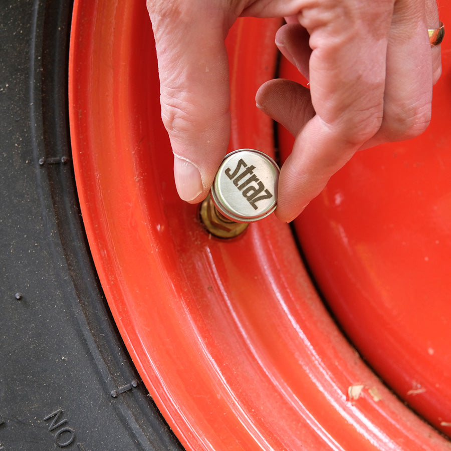Person using a Straz Components Schrader Valve Core Remover on a tractor wheel.