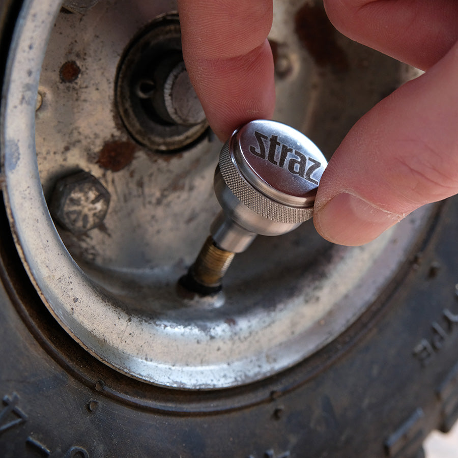 Person using a Straz Components Schrader Valve Core Remover on a utility wheel.